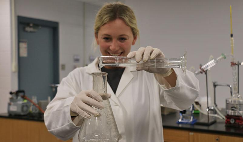 Peyton pouring liquid into a conical flask